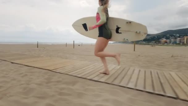 Giovane bella donna con tavola da surf in spiaggia — Video Stock