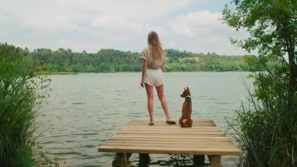 Vrouwelijke reiziger met haar hond op meerpromenade — Stockvideo