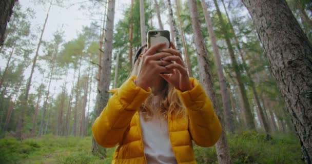Giovane donna nella foresta fare foto o il segnale di ricerca — Video Stock