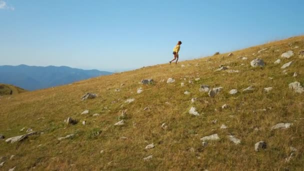 Mulher em shorts subir colina no fundo do céu azul — Vídeo de Stock