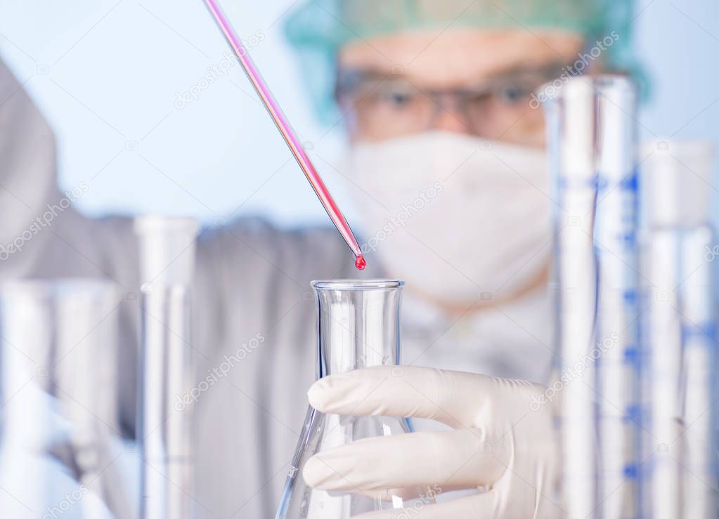 Scientist with pipette and glass flasks