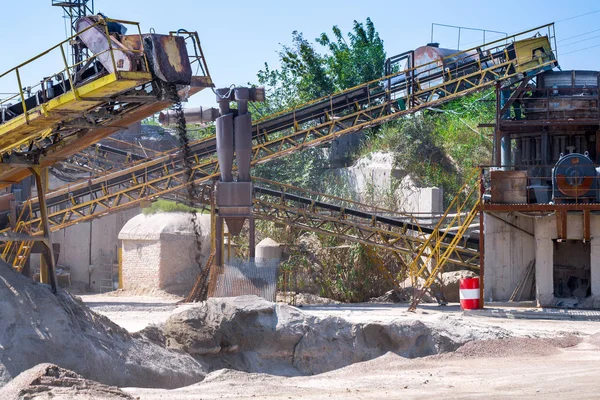 Crushing machinery, cone type rock crusher, conveying crushed granite gravel stone in a quarry open pit mining. Processing plant for crushed stone and gravel. Mining and Quarry mining equipment.