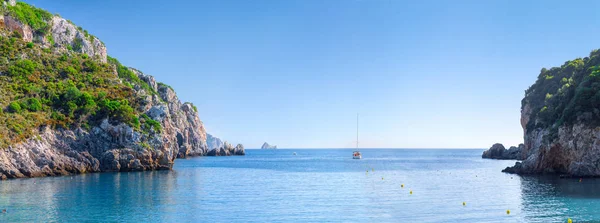 Beautiful summer panoramic seascape. View of the cliff into the sea bay with crystal clear azure water in sunshine daylight. Boats and yachts in the harbor. Mediterranean sea, somewhere in Europe.