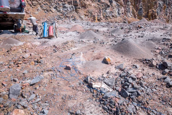 Derin yüzey sondaj kulesi taş ocağında granit madenciliği. Üretim taşları ve çakılları işleyin. Taş ocağı maden ekipmanları. Tanımlanamayan yüzleri bulanık işçiler. Patlatma için hazırlama.