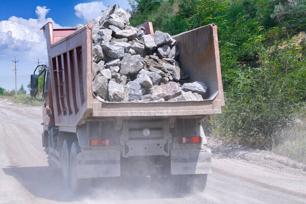 A dump truck loaded mined granite in a quarry open pit mining of granite stone. Process production stone and gravel. Quarry mining equipment.
