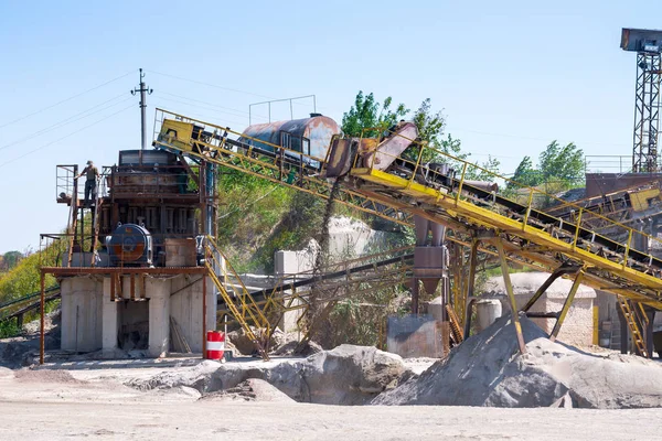 Crushing machinery, cone type rock crusher, conveying crushed granite gravel stone in a quarry open pit mining. Processing plant for crushed stone and gravel. Mining and Quarry mining equipment.