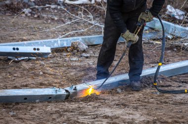 Bir işçi propan-oksijen meşalesi kullanarak çelik kirişler kesti