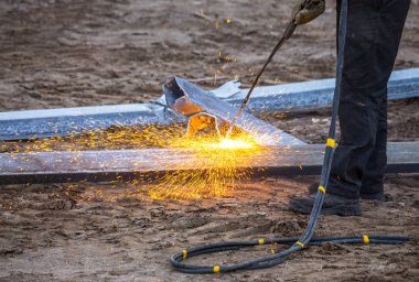 Bir işçi propan-oksijen meşalesi kullanarak çelik kirişler kesti