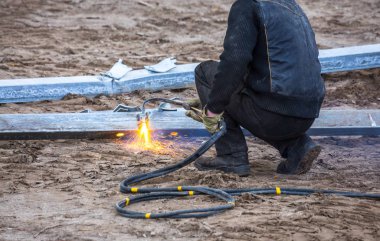 Bir işçi propan-oksijen meşalesi kullanarak çelik kirişler kesti