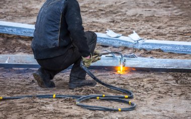 Bir işçi propan-oksijen meşalesi kullanarak çelik kirişler kesti
