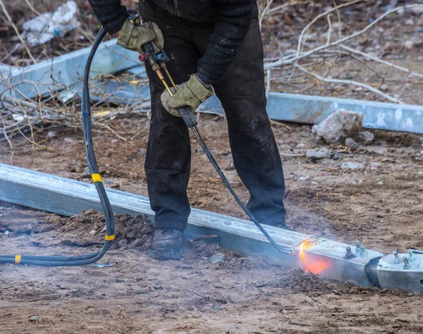 A worker cut steel beams using propane-oxygen torch