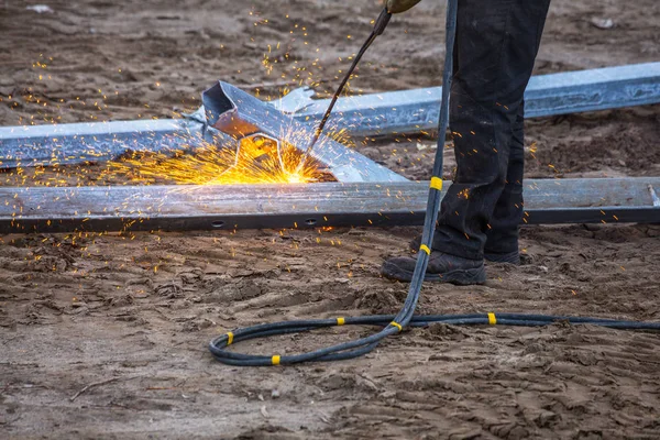 A worker cut steel beams using propane-oxygen torch