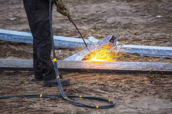 A worker cut steel beams using propane-oxygen torch