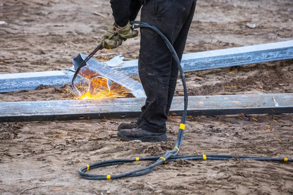 A worker cut steel beams using propane-oxygen torch