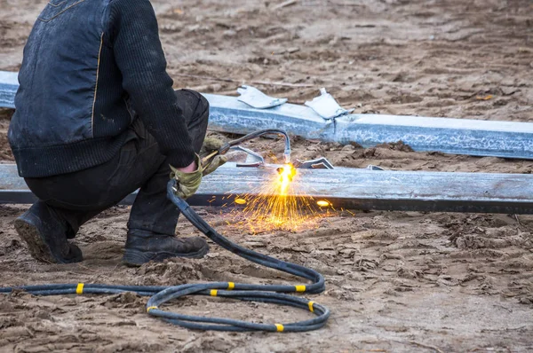 A worker cut steel beams using propane-oxygen torch