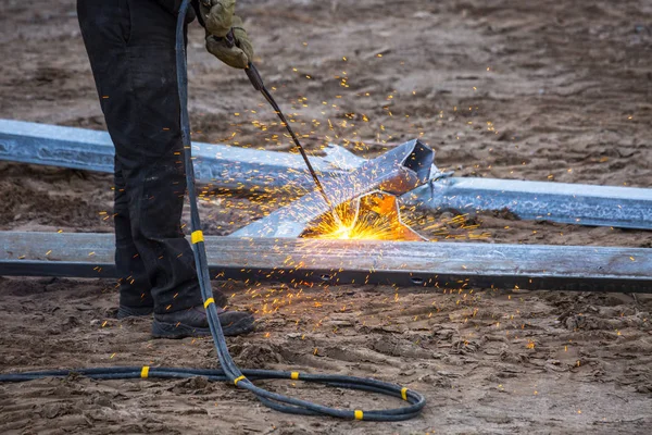 A worker cut steel beams using propane-oxygen torch