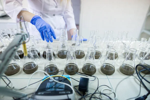 Händerna på vetenskapsmannen i laboratoriet skaka en glasflaskor med d — Stockfoto