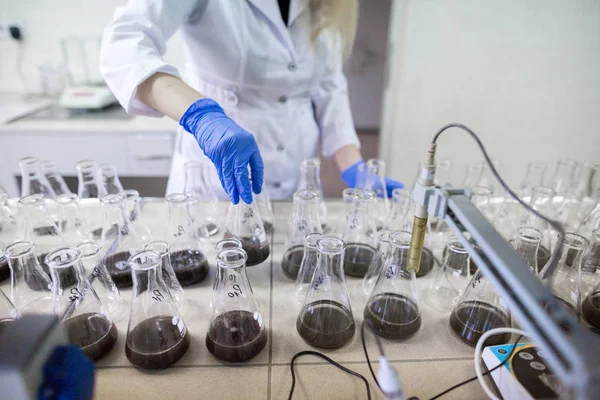 Händerna på vetenskapsmannen i laboratoriet skaka en glasflaskor med d — Stockfoto