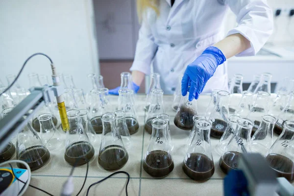 Händerna på vetenskapsmannen i laboratoriet skaka en glasflaskor med d — Stockfoto