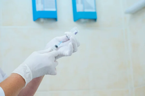 Hoitajan käsi pitäen ruiskua ja injektiopullon annosta rokotteella tai lääkkeillä — kuvapankkivalokuva