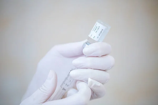 Hoitajan käsi pitäen ruiskua ja injektiopullon annosta rokotteella tai lääkkeillä — kuvapankkivalokuva