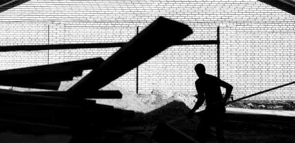 Un trabajador descarga en la construcción de tablas de madera en un respaldo — Foto de Stock