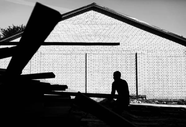 Un trabajador descarga en la construcción de tablas de madera en un respaldo — Foto de Stock