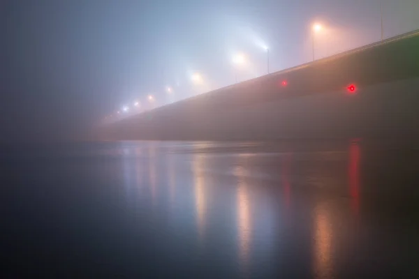 Een mysterieuze avond mist boven de rivier in de grote stad. Brug in — Stockfoto