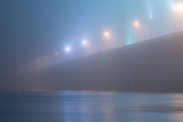 Uma noite misteriosa neblina acima do rio na cidade grande. Ponte em — Fotografia de Stock