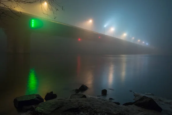 Uma noite misteriosa neblina acima do rio na cidade grande. Ponte em — Fotografia de Stock