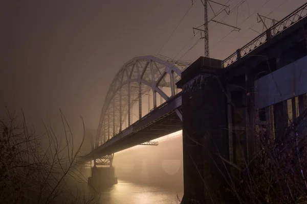 Uma noite misteriosa neblina acima do rio na cidade grande. Ponte em — Fotografia de Stock