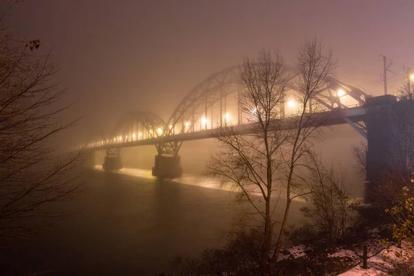 Uma noite misteriosa neblina acima do rio na cidade grande. Ponte em — Fotografia de Stock