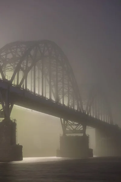 Uma noite misteriosa neblina acima do rio na cidade grande. Ponte em — Fotografia de Stock