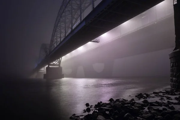 Salaperäinen iltasumu joen yläpuolella suurkaupungissa. Komentosilta — kuvapankkivalokuva