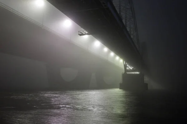 Uma noite misteriosa neblina acima do rio na cidade grande. Ponte em — Fotografia de Stock