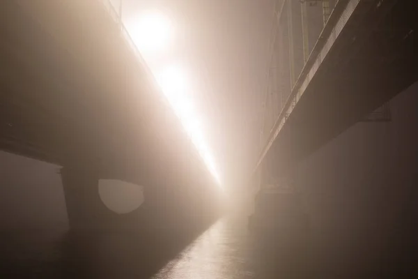 Una misteriosa nebbia serale sopra il fiume nella grande città. Ponte in — Foto Stock