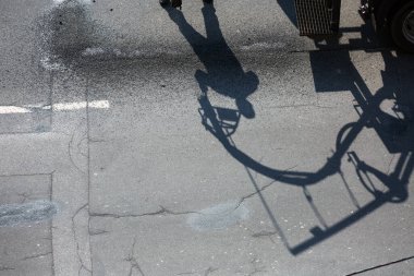 Yol yenileme işi. Yol yamasında çalışan işçilerin gölgesi, yarıkların onarılması için ziftlerle kaplanarak ve asfalt yüzeyinde kuru kümelenerek çalışırlar..