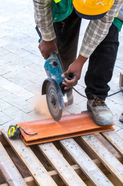 Asfalt inşaatı. Kaldırıma beton kaldırım taşları yerleştirildi. Bir işçi disk kesiciyle ölçümler yapar, işaretler ve keser..