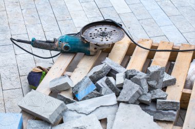 Asfalt inşaatı. Kaldırıma beton kaldırım taşları yerleştirildi. Tahta bir palette duran disk kesici..