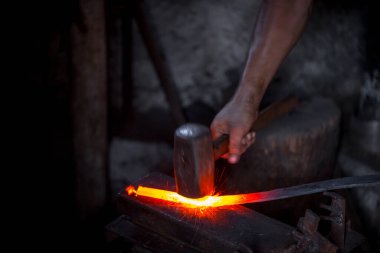 Demircinin elleri iş başında. Bir elinde çekiç, diğer elinde sıcak metalden bir iş parçası. Usta düzenli olarak örse vuruyor. Eski el sanatlarının sıkı çalışmasına bir örnek..