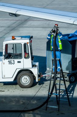 Havaalanının bir çalışanı tankeri çalıştırıyor ve uçağı havacılık yakıtıyla dolduruyor..