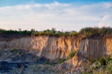 Kazı kovası küçük bir tuğla fabrikası için kil ocağında iz bırakıyor. Endüstriyel alanda akşam güneşi.