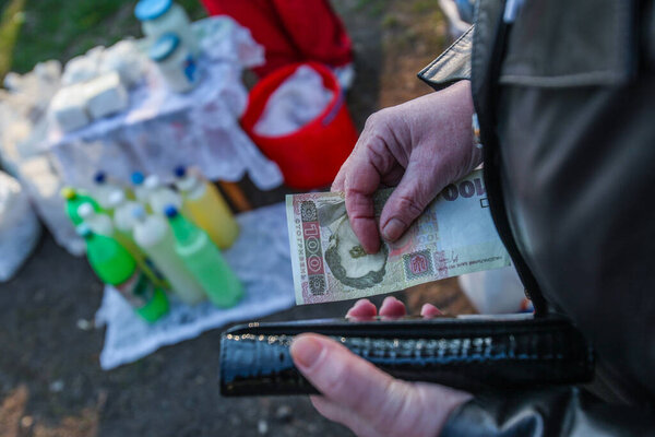 Воскресная ярмарка в небольшом селе в центральной Украине Черкасской области. Лицо покупателя крестьянин держит в руке бумажник и банкноту в размере 100 грн. Молоко в ПЭТ бутылки.