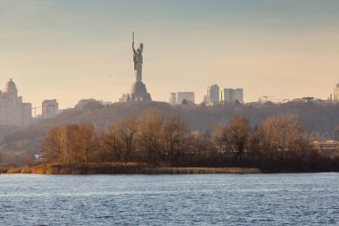 Geniş nehrin üzerindeki tepedeki büyük şehrin muhteşem, parlak günbatımı manzarası. Kyiv. Ukrayna.
