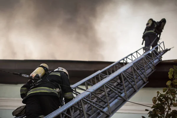 Brandweerlieden Ladders Met Zuurstofmaskers Blussen Het Vuur Een Oud Huis — Stockfoto