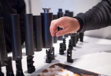 Modern saldırı tüfeklerinin flaş susturucuları ya da namlu frenleri. Farklı kalibre modern silahlar için susturucular, ses susturucular ya da ses moderatörleri. Adamın eli cihazı elinde tutuyor..