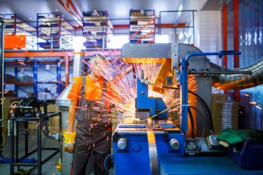 Metal ürünlerinin endüstriyel üretiminde kaynak makinesi üzerinde çalışan erkek bir tamirci. Parçaların altından kıvılcımlar çıkıyor. Konsept tema onarımı, mekanik, üretim, endüstri. Tanımlanamayan yüz