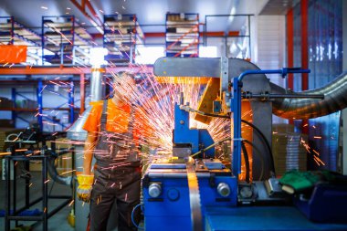 Metal ürünlerinin endüstriyel üretiminde kaynak makinesi üzerinde çalışan erkek bir tamirci. Parçaların altından kıvılcımlar çıkıyor. Konsept tema onarımı, mekanik, üretim, endüstri. Tanımlanamayan yüz