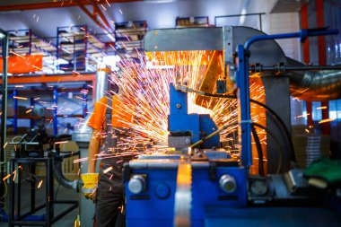 Metal ürünlerinin endüstriyel üretiminde kaynak makinesi üzerinde çalışan erkek bir tamirci. Parçaların altından kıvılcımlar çıkıyor. Konsept tema onarımı, mekanik, üretim, endüstri. Tanımlanamayan yüz