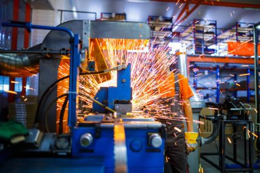 Metal ürünlerinin endüstriyel üretiminde kaynak makinesi üzerinde çalışan erkek bir tamirci. Parçaların altından kıvılcımlar çıkıyor. Konsept tema onarımı, mekanik, üretim, endüstri. Tanımlanamayan yüz